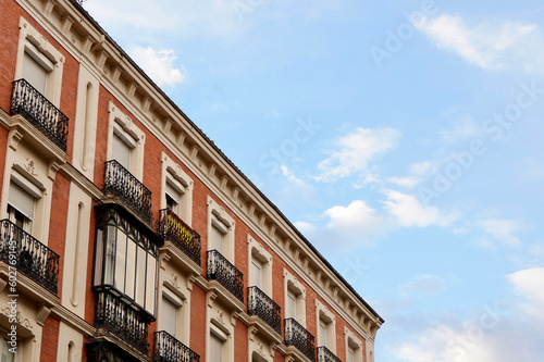 Front view on antique facade made of red brick with retro metallic balconies in Madrid, Spain. Vintage architecture. Old fashioned living