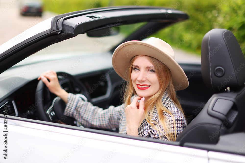 Naklejka premium Portrait of Young blond girl in a hat driving cabriolet