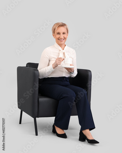 Mature businesswoman drinki...