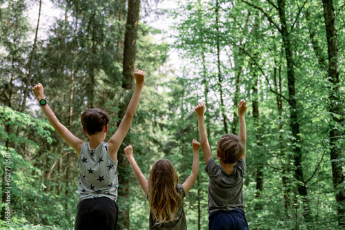 Three kids enjoying life standing next to each other with arms raised high in the air