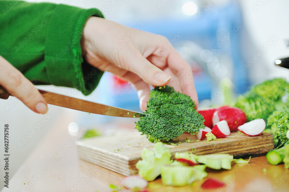 woman preparing healthy food salad with green and red vegetable and knife