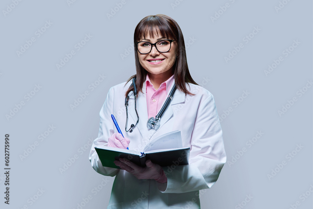 Female doctor taking note information in notebook on grey background Female doctor taking note information in notebook on grey background