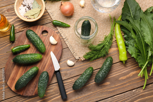 Fresh cucumbers and ingredients for preservation on wooden background