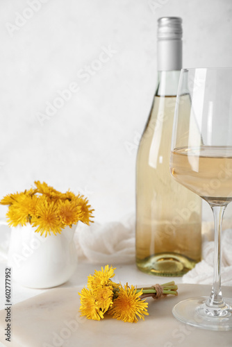 Bottle and glass of dandelion wine on white table