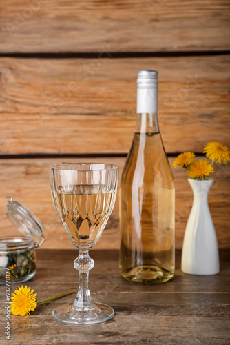 Bottle and glass of dandelion wine on wooden table