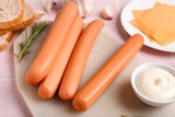 Board of tasty sausages with rosemary and mayonnaise on pink tile background