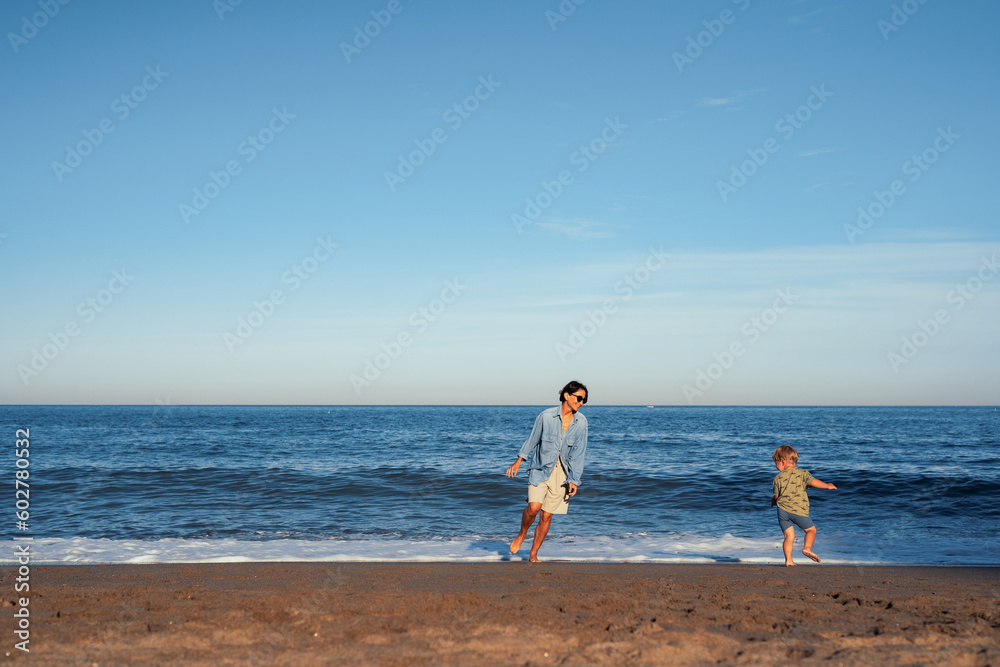 mom and little son run on the sand on the seashore happiness joy