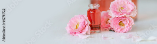 Concept of perfume with pure natural organic rose ingredient, essential oils. Glass bottles with flower herbal extract and elixir. Perfumery cosmetic toilet water fragrance, banner copy space for text