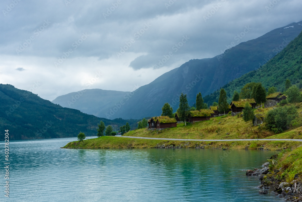 Fototapeta premium Wooden rorbus, typical houses with grass on the roof, on the Lovatnet Lake, Norway