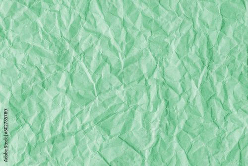 Recycled crumpled light green paper texture background. Wrinkled and creased abstract backdrop, wallpaper with copy space, top view.