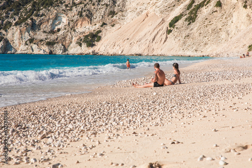 Young family rests on the Myrtos beach, Kefalonia island, Greece during summer sea vacation.