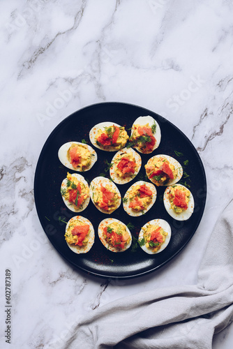 Homemade deviled eggs with salmon on a black background.