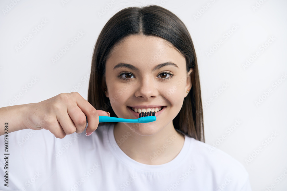 Headshot of a cute teenager girl brushing teeth with toothbrush, isolated on white studio background Headshot of a cute teenager girl brushing teeth with toothbrush, isolated on white studio background