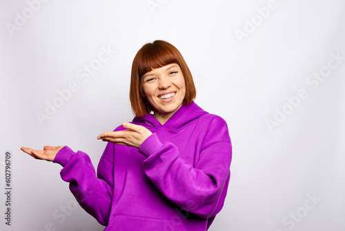 Woman in a purple hoody is showing aside. Isolated