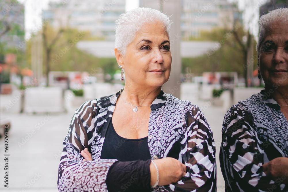 older gray-haired latin business woman reflected in glass with her arms folded older gray-haired latin business woman reflected in glass with her arms folded
