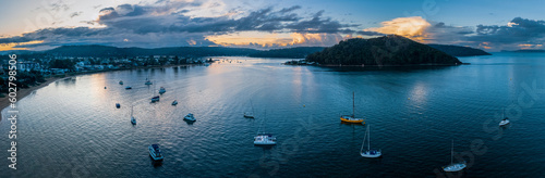 Aerial sunrise waterscape panorama with scattered rain clouds and boats