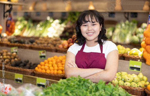 Smiling young saleswoman posing happily in front of counter in grocery store with large assortment © JackF