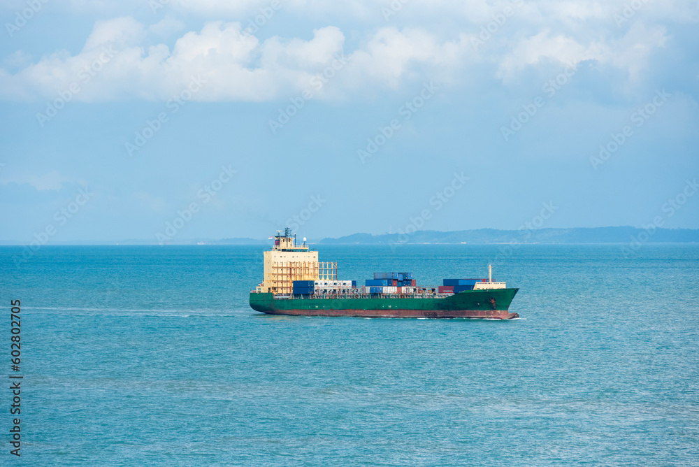 Cargo container ship sailing through peaceful, calm, blue sea on her voyage through the Singapore Strait. Cargo container ship sailing through peaceful, calm, blue sea on her voyage through the Singapore Strait.