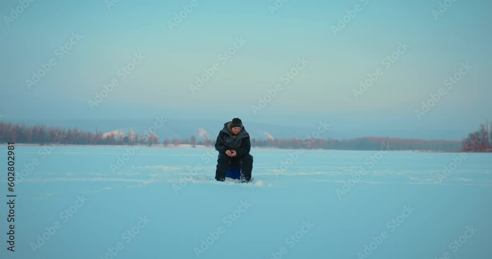 lonely man practicing ice fishing in early morning, sitting on frozen river in winter, 4K, Prores lonely man practicing ice fishing in early morning, sitting on frozen river in winter, 4K, Prores