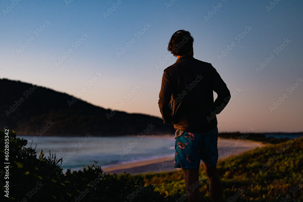 Silhouette image of man standing on Jimmy's Beach early in the morning at Hawks Nest NSW Australia