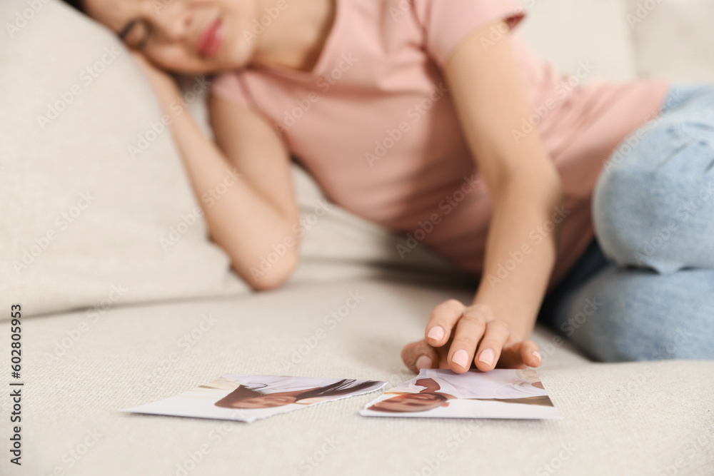 Upset woman with parts of torn photo on sofa, selective focus. Divorce concept Upset woman with parts of torn photo on sofa, selective focus. Divorce concept
