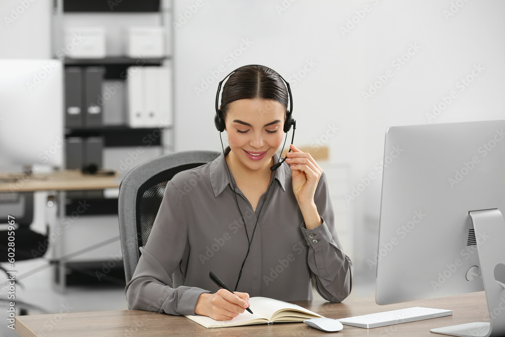 Hotline operator with headset and notebook working in office Hotline operator with headset and notebook working in office