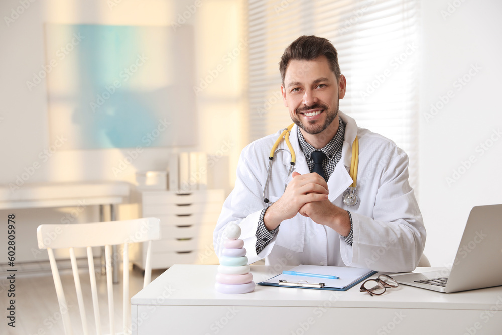 Pediatrician with stethoscope at table in clinic Pediatrician with stethoscope at table in clinic