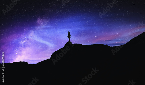 Silhouette of woman in mountains under beautiful starry sky at night