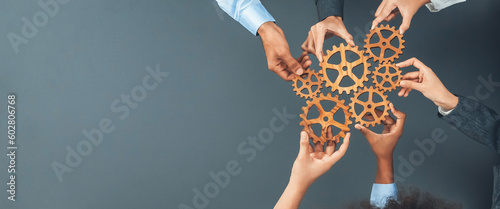 Fotografie, Obraz Panoramic shot top view of business people holding cog wheel as unity and teamwork in corporate workplace concept