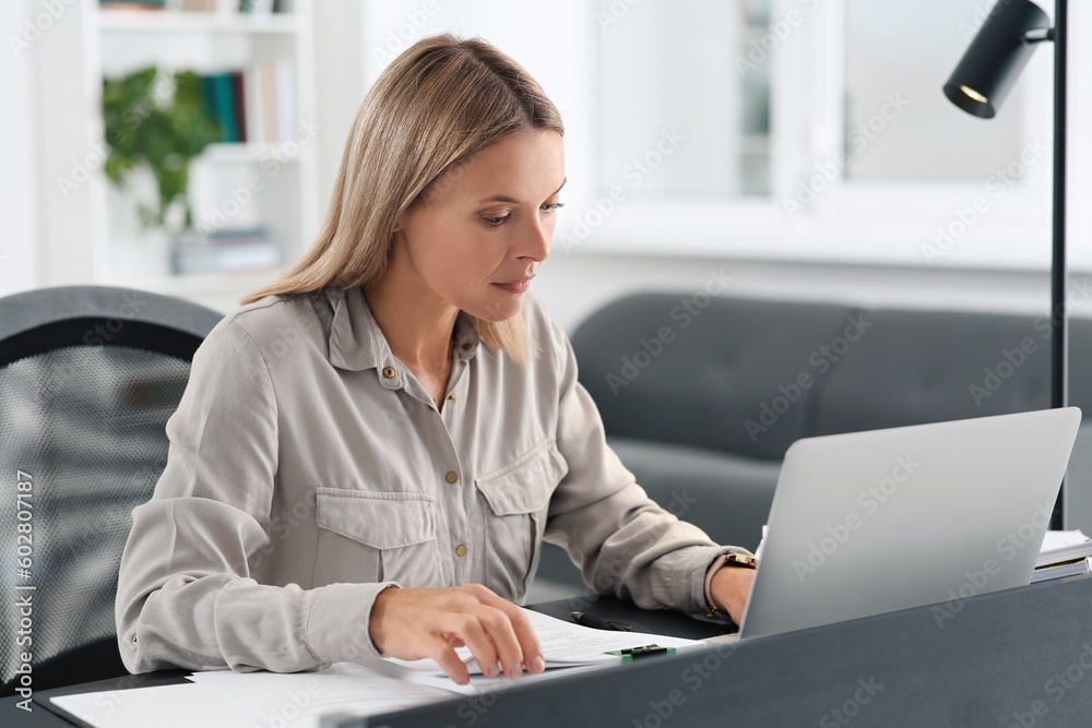 Businesswoman working with documents at grey table in modern office Businesswoman working with documents at grey table in modern office