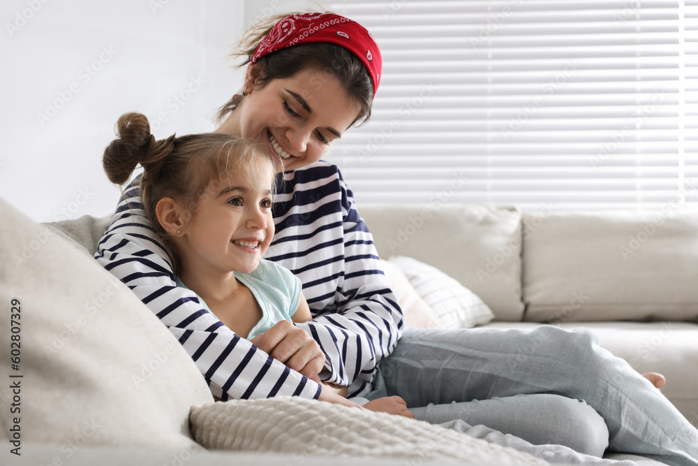 Young mother and her daughter spending time together on sofa at home