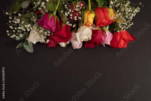 Bunch of colorful roses on a black background with copy space