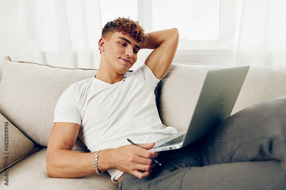 man happy t-shirt browsing indoor typing phone modern job laptop chat couch man happy t-shirt browsing indoor typing phone modern job laptop chat couch