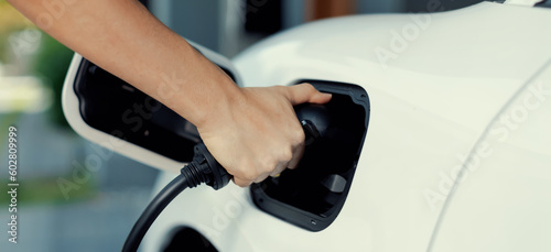 Progressive concept of hand insert an emission-free power connector to the battery of electric vehicle at home. Electric vehicle charging via cable from charging station to EV car battery