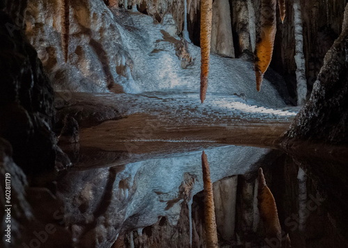 stalagtites reflected in clear pool in cave photo
