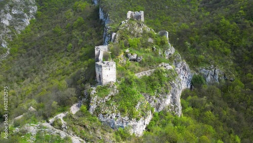 Aerial forward video of ruins of the old fortress Sokograd, amazing view of green vegetation which grow around and visitors enjoying the adventure 4K 60fps photo
