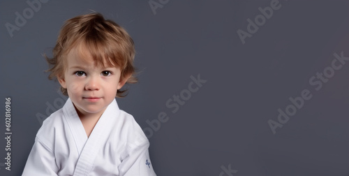 a smiling europe's boy child dressed as a martial arts athletes in soft solid dark grey background generative ai photo