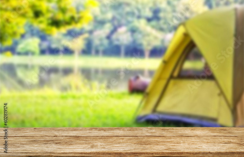 Wooden table top on blur tent camping travel tent and grass field.Fresh and Relax concept.For montage product display or design key visual layout.View of copy space.