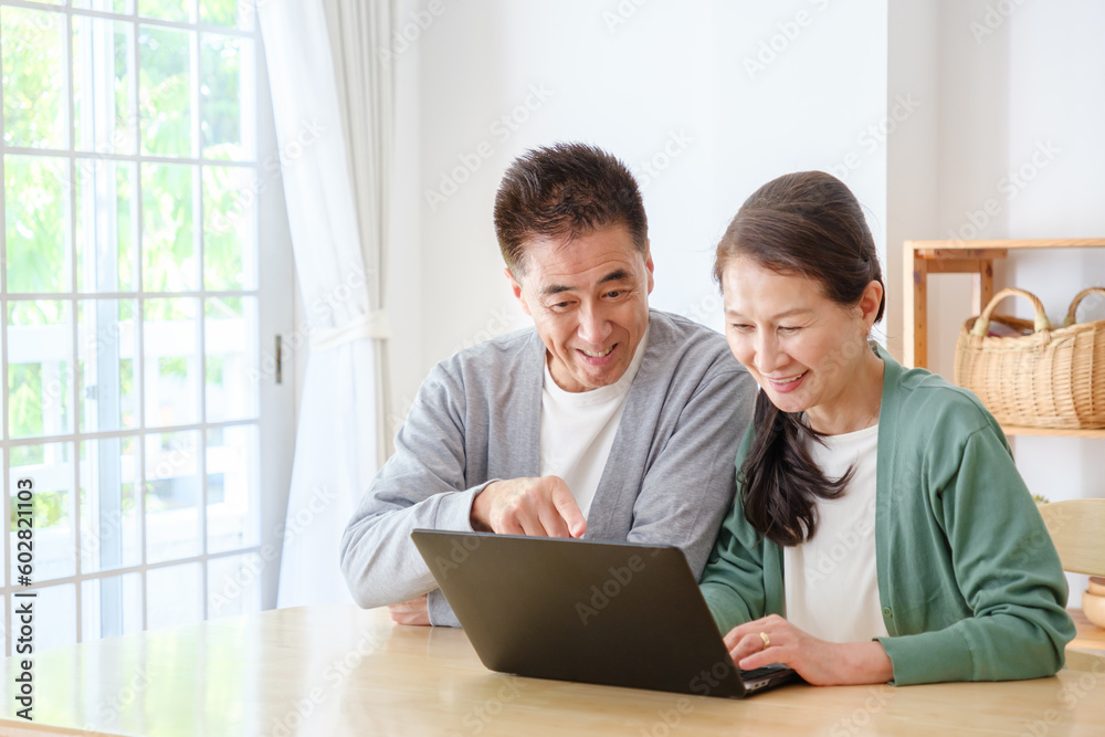 リビングでパソコンを使うシニア夫婦 リビングでパソコンを使うシニア夫婦