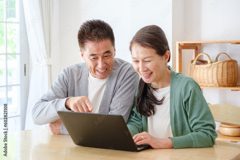 リビングでパソコンを使うシニア夫婦 リビングでパソコンを使うシニア夫婦