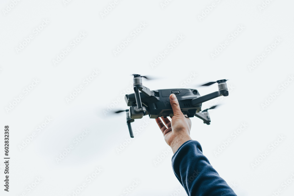 Photograph of hands holding a drone in the air (Drone Operator). Technology concept
