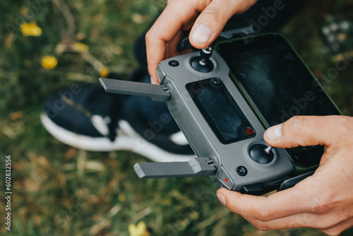 Photograph of a man's hands holding the remote control of a Drone (Drone Operator). Technology concept