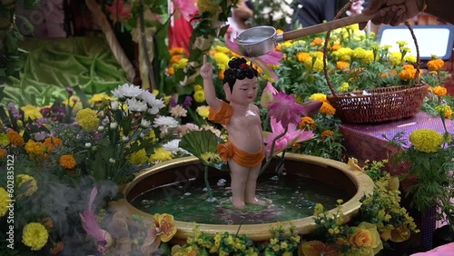 A devotee baths a statue of Buddha during Vesak Day
