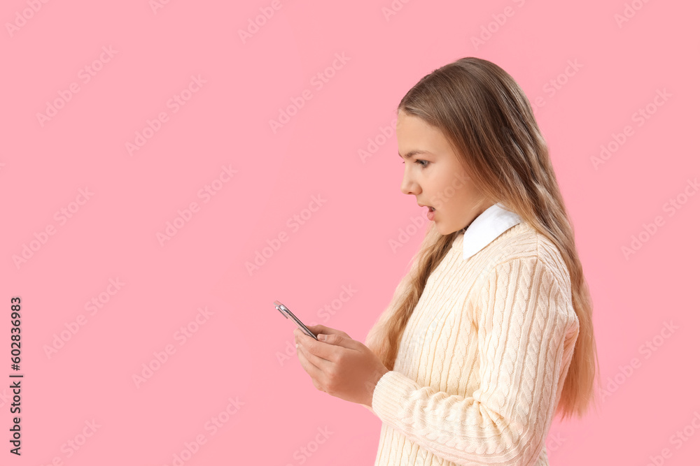 Shocked little girl using mobile phone on pink background Shocked little girl using mobile phone on pink background