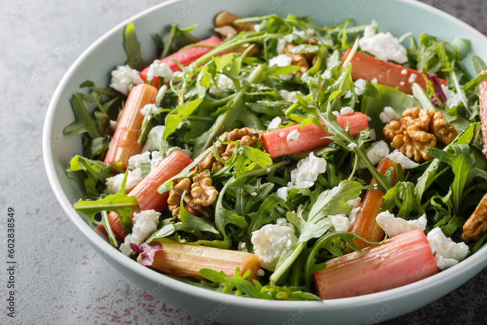 Homemade mix salad with baked rhubarb, arugula, goat cheese and walnuts close-up in a bowl on the table. Horizontal