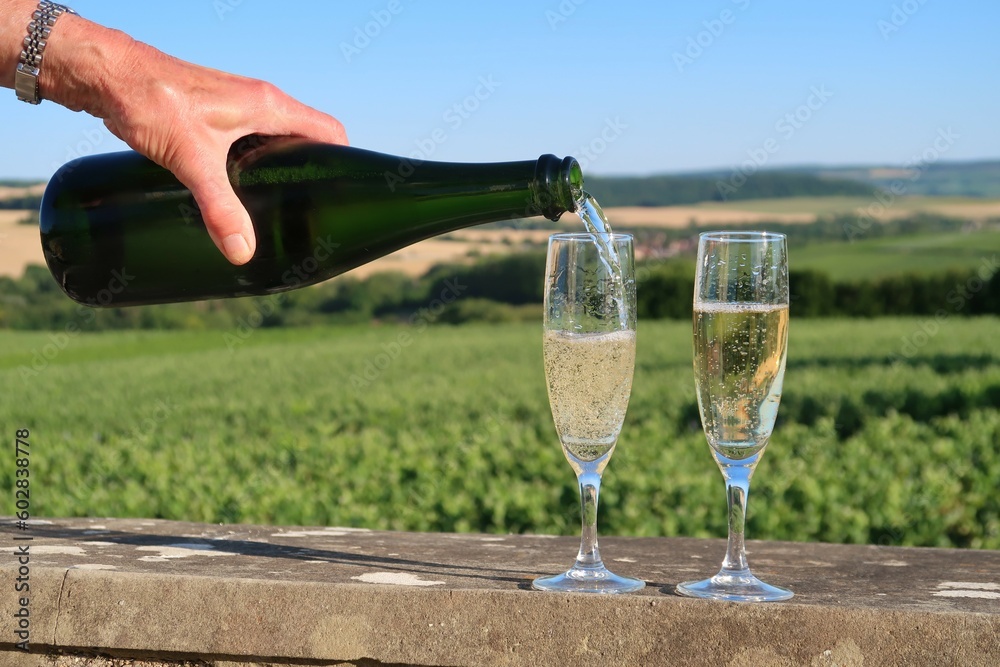 Main de femme tenant une bouteille de champagne et versant le vin dans deux verres (flûtes