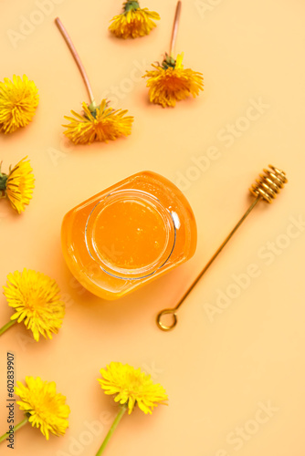 Jar with dandelion honey on orange background