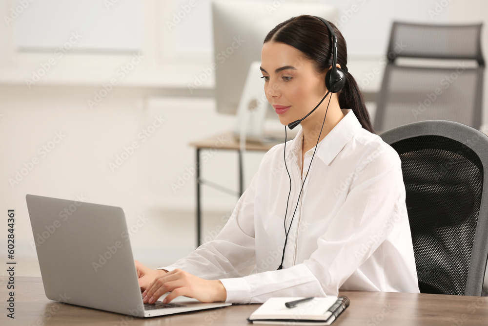 Hotline operator with headset working on laptop in office Hotline operator with headset working on laptop in office