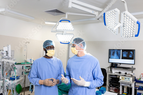 Two diverse male surgeons discussing before operation in operating theatre
