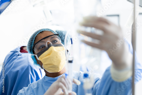 Asian female surgeon checking drip bag during surgery in operating theatre